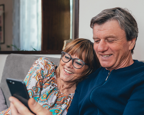 senior couple smiling on couch at phone retirement future ma